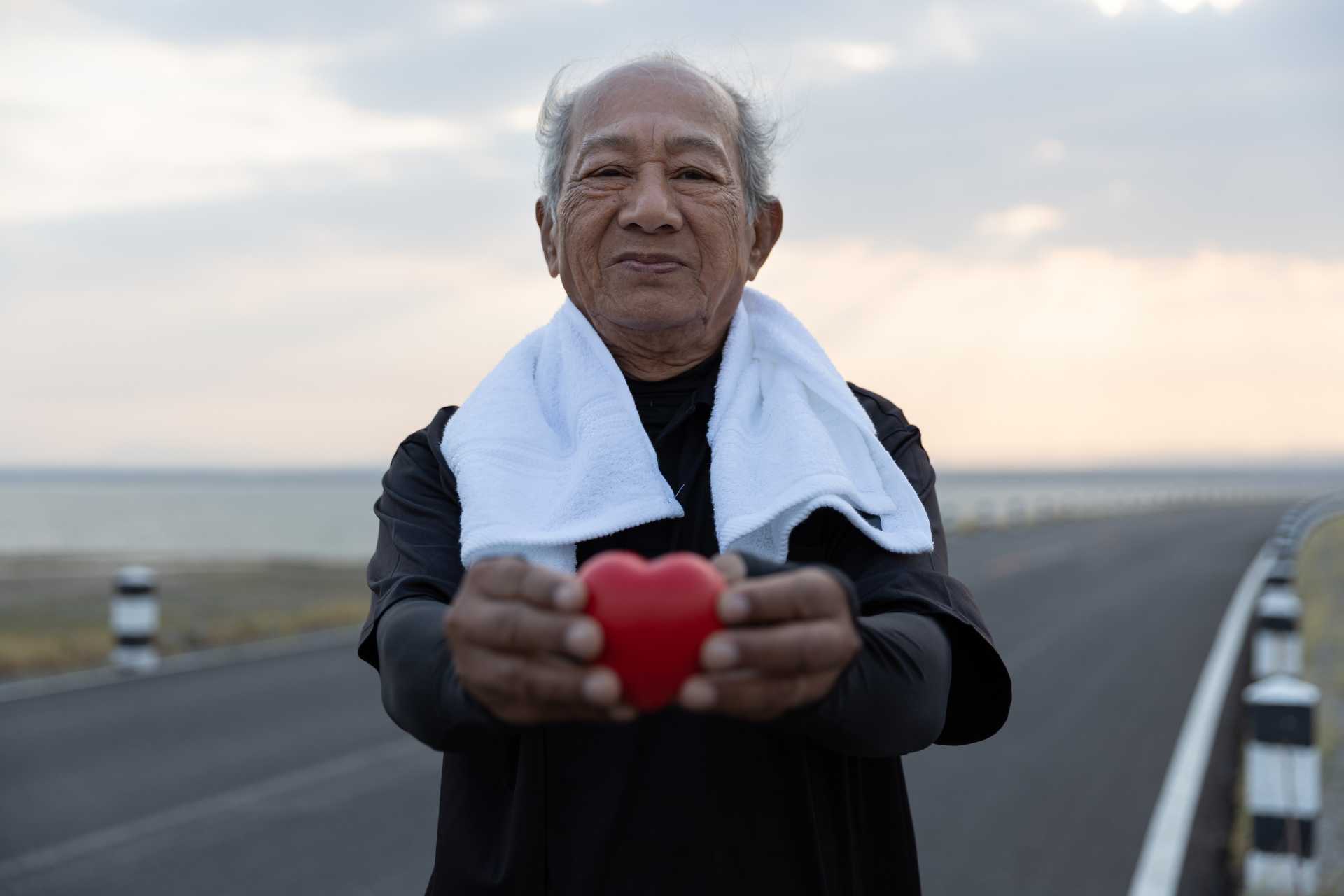 SeniorHeartHealth A senior man on a run, holding a red heart shape.